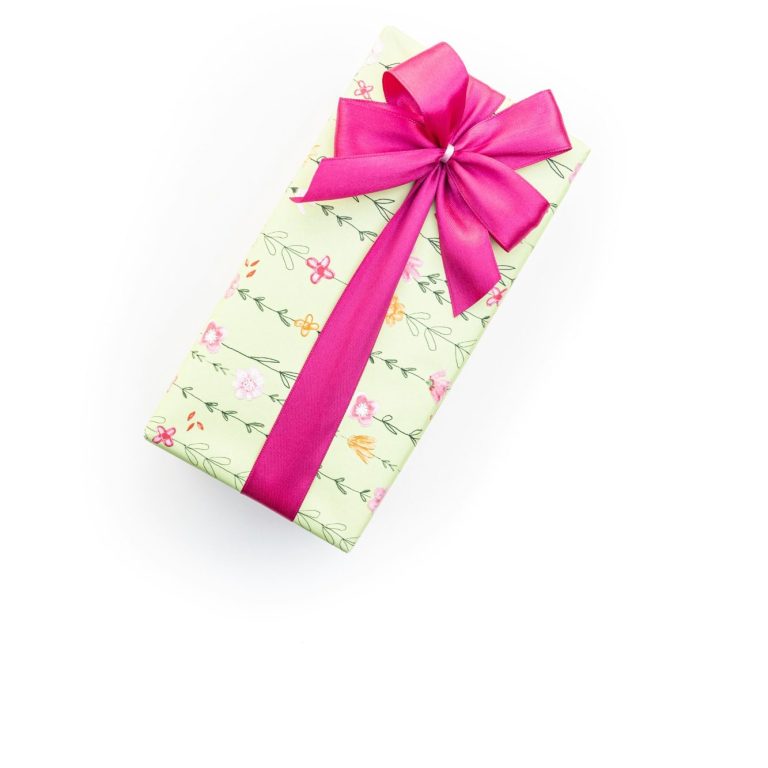 A gift wrapped in green and pink wrapping paper with a flower design on, tied with a bright pink elegant bow.